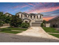 Charming two-story home featuring a well-maintained lawn and a long driveway leading to an attached garage at 12120 Sumter Dr, Orlando, FL 32824