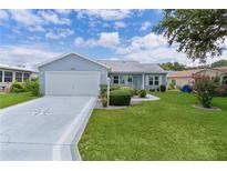 Charming single-story home with a well-manicured lawn, tidy landscaping, and a two-car garage at 1225 Zapata Pl, The Villages, FL 32159