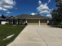 Charming single story home featuring a 3-car garage, manicured lawn, and American flag at 13109 Laurel Crest Ct, Grand Island, FL 32735