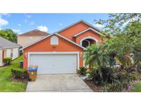 Charming orange two-story home with a two car garage and tropical landscaping at 167 Castaway Beach Way, Kissimmee, FL 34746