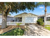 Charming home featuring a white picket fence, mature trees, and attached garage at 16938 Se 94Th Sunnybrook Cir, The Villages, FL 32162