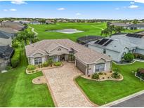 Beautiful single-story home with a paver driveway and lush landscaping overlooking a golf course and pond at 17599 Se 121St Cir, Summerfield, FL 34491
