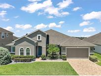 Charming one-story home boasts a manicured lawn, two-car garage, and a blue entry door at 2136 Lula Rd, Minneola, FL 34715