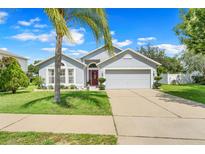 Charming single-story home with a well-maintained lawn, red front door, and a two-car garage at 3213 White Blossom Ln, Clermont, FL 34711