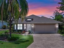 Charming single Gathering home boasting a lush lawn, mature trees, and a paved driveway at dusk at 4814 Saint Andrews Arc, Leesburg, FL 34748