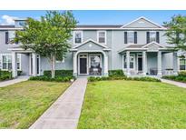 Inviting two-story townhome with well-manicured lawn and charming front porch seating at 520 Rainbow Springs Loop, Groveland, FL 34736
