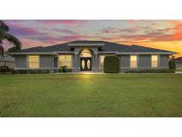 Beautiful single-story home features a sprawling lawn and a symmetrical facade under a vibrant sunset sky at 5412 County Road 125, Wildwood, FL 34785