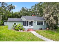 Charming single-story home featuring a screened-in porch and landscaped front yard with mature trees at 601 S 12Th St, Leesburg, FL 34748