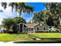 Charming one-story home with a manicured lawn and mature trees, creating a welcoming curb appeal at 681 Greywood Dr, Altamonte Springs, FL 32701