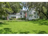 Beautiful two-story home with lush green lawn, mature landscaping, and an American flag displayed in front at 9223 Silver Lake Dr, Leesburg, FL 34788