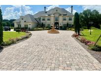 Elegant two-story home with a fountain, manicured lawn, and paver driveway at 10301 Savannah Ridge Ln, Winter Garden, FL 34787