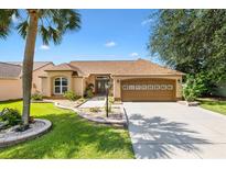 Charming single-story home with a well-maintained lawn, mature landscaping, and a two-car garage at 1032 Ventura Dr, Lady Lake, FL 32159