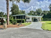 Charming home featuring a screened porch, carport, and well-maintained landscaping at 113 Temple W Cv, Leesburg, FL 34748