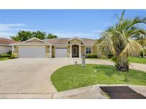 Charming single-story home featuring a well-manicured lawn, mature palm tree, and a spacious three-car garage at 12407 Ne 48Th Loop, Oxford, FL 34484