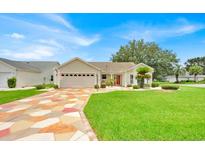 Charming single-story home with well-manicured lawn, colorful driveway, and attached two-car garage at 1401 Madrigal Ln, Lady Lake, FL 32159