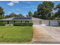 Charming single-story home with a well-manicured lawn, metal roof and three car garage at 2450 W Lake Dr, Deland, FL 32724