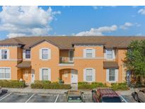 A sunny, orange two-story townhome with a brown roof, white trim, and well-maintained landscaping at 2717 Bushman Dr, Kissimmee, FL 34746