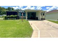 Cozy single-story home featuring a well-manicured lawn, covered parking, and charming screened-in porch area at 902 Rose Ln, Lady Lake, FL 32159
