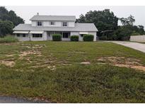 Two-story home featuring a spacious yard, covered parking, and mature trees at 11532 Beaman Cir, Clermont, FL 34711