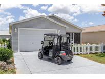 Charming single-story home with a well-maintained lawn and a golf cart parked in the driveway at 1334 Hollyberry Pl, The Villages, FL 32162