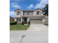 Two-story home featuring neutral-toned exterior, attached two car garage and green lawn at 149 Roseling Xing, Davenport, FL 33897