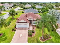 Well-maintained single-Gathering home features a large driveway with a beautiful lawn and tropical landscaping at 1722 Bugle Ter, The Villages, FL 32162