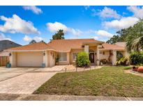 Charming single-story home featuring manicured landscaping, a brick-paved driveway, and a two-car garage at 3309 Paisley Cir, Orlando, FL 32817