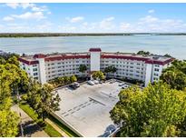 Waterfront condo building featuring a red tile roof, well-maintained landscaping, and ample parking at 601 N Mcdonald St # 2, Mount Dora, FL 32757