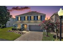 Charming two-story home featuring a manicured lawn, brick driveway, and inviting front porch at 621 Lost Grove Cir, Winter Garden, FL 34787