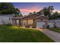 Charming single Gathering home with manicured lawn, brick accents, and warm exterior lighting at dusk at 149 Shiloh Ave, Lady Lake, FL 32159