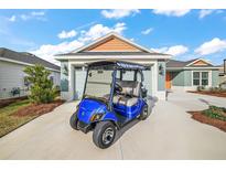 View of the home's exterior featuring a Yamaha golf cart parked in the driveway and a two car garage at 2055 Merideth Ter, The Villages, FL 34762