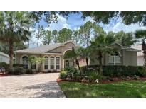 Charming single-story home featuring manicured landscaping, a brick driveway, and beautiful arched windows at 2299 Twickingham Ct, Clermont, FL 34711