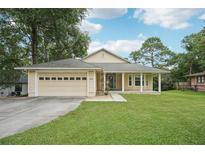 Charming single-story home featuring a covered front porch, two-car garage, and well-maintained lawn at 2342 Robert D Rd, Mount Dora, FL 32757