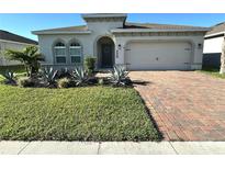 Charming single-story home with a well-manicured lawn, desert landscaping, and a brick driveway at 295 Whirlaway Drive, Davenport, FL 33837