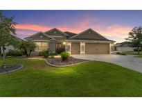 Charming one-story home featuring a well-maintained lawn, mature landscaping, and a spacious three-car garage at 3750 Raspberry Ct, The Villages, FL 32163