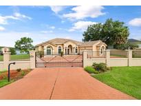Stately home with a brick driveway, decorative iron gate, manicured lawn and view of the lake at 10839 Lakeshore Dr, Clermont, FL 34711