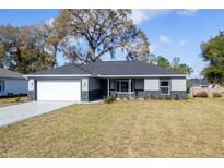 Charming single-story home with a gray exterior, stone accents, landscaped yard, and a two-car garage at 781 Ne 130Th Ter, Silver Springs, FL 34488