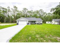 Charming single-story home with attached garage, and a well-manicured lawn at 1243 Ne 130Th Ter, Silver Springs, FL 34488