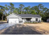 Charming single-story home with gray siding, a new roof, an attached garage, and an adjacent patch of landscaping at 1243 Ne 130Th Ter, Silver Springs, FL 34488