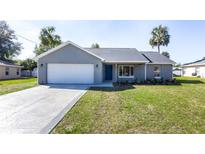 Charming single-story home featuring a two-car garage, blue front door, and a well-manicured lawn at 600 Ne 130Th Ter, Silver Springs, FL 34488