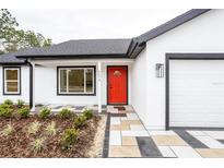 Modern white house with red door, gray stone walkway, and landscaping at 600 Ne 130Th Ter, Silver Springs, FL 34488