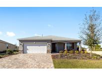 Charming single-story home with a well-manicured lawn, stone accents, and a brick paved driveway at 8731 Sw 76Th Street Rd, Ocala, FL 34481