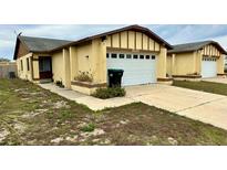 Cute yellow exterior of a twin home with a white garage door and small front yard at 1326 Spring Lite Way, Orlando, FL 32825