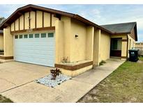 Tan house with white garage door and landscaping at 1328 Spring Lite Way, Orlando, FL 32825