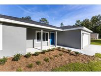 Inviting one story home featuring a blue front door, fresh landscaping, and an attached one car garage at 24009 Sw Huckleberry Ln, Dunnellon, FL 34431