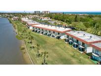 An aerial view of a waterfront condo complex with manicured lawns and mature palm trees at 26 Ocean Palm Villa S # 26, Flagler Beach, FL 32136