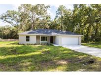 Charming single-story home featuring a two-car garage, well-maintained lawn, and complemented by mature trees at 18 Malauka Loop Pass, Ocklawaha, FL 32179