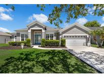 Charming gray home featuring a well-manicured lawn, lush landscaping, and a two-car garage at 14867 Bonnybridge Dr, Orlando, FL 32826