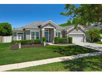 Charming single-story home featuring a well-manicured lawn, lush landscaping, and a bright blue front door at 14867 Bonnybridge Dr, Orlando, FL 32826