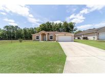 Charming single-story home with a well-manicured lawn and a spacious driveway leading to an attached garage at 2648 Ne 24Th Pl, Ocala, FL 34470
